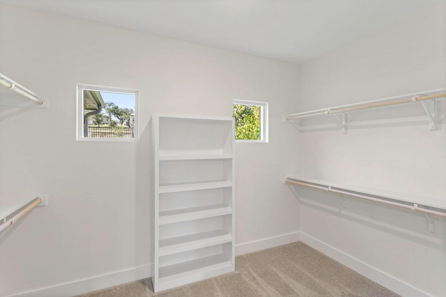 Spacious walk-in closet featuring built-in shelving, multiple hanging rods, and an integrated multi-level bookcase Spacious walk-in closet featuring built-in shelving, multiple hanging rods, and an integrated multi-level bookcase