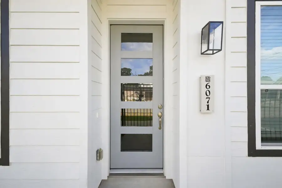 Modern front entry featuring a contemporary glass-panel door, clean architectural details, and exterior lighting. Modern front entry featuring a contemporary glass-panel door, clean architectural details, and exterior lighting.