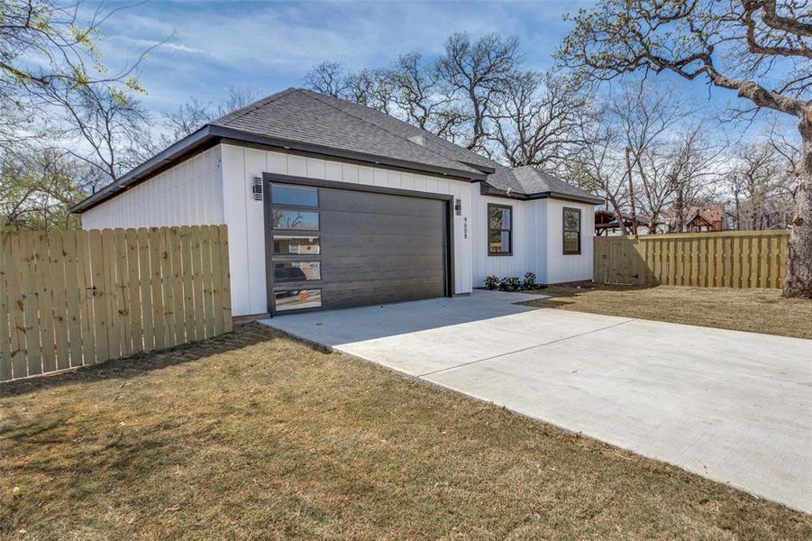 View of home's exterior featuring fence, a yard, concrete driveway, an attached garage, and a shingled roof