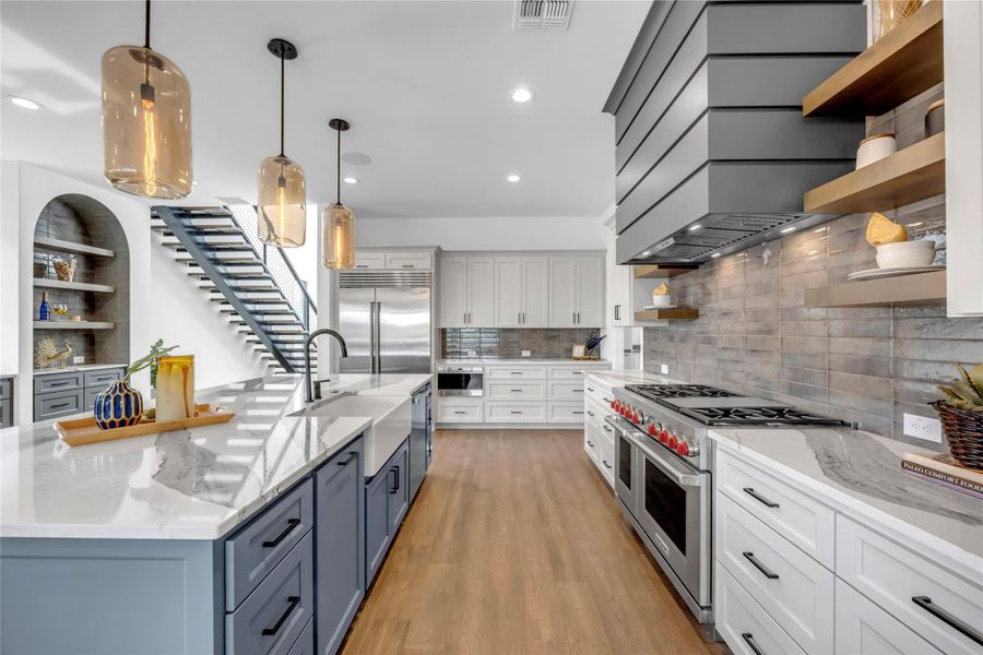 Kitchen featuring open shelves, light stone counters, decorative light fixtures, high quality appliances, and recessed lighting