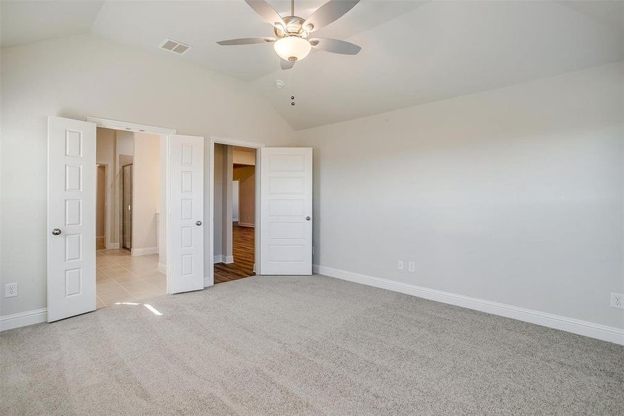 Unfurnished bedroom with ceiling fan, light carpet, and vaulted ceiling