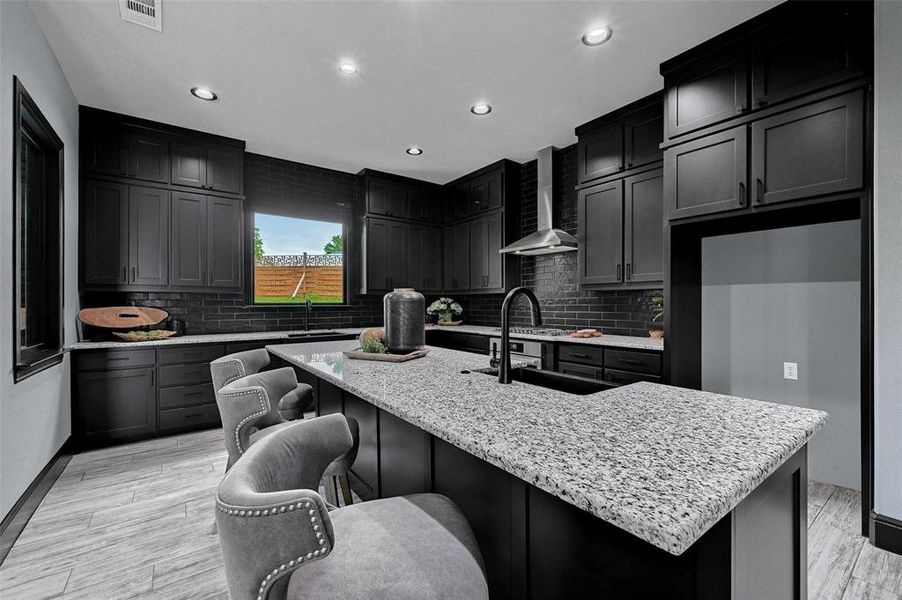 Kitchen with wall chimney exhaust hood, recessed lighting, decorative backsplash, a sink, and light stone counters Kitchen with wall chimney exhaust hood, recessed lighting, decorative backsplash, a sink, and light stone counters
