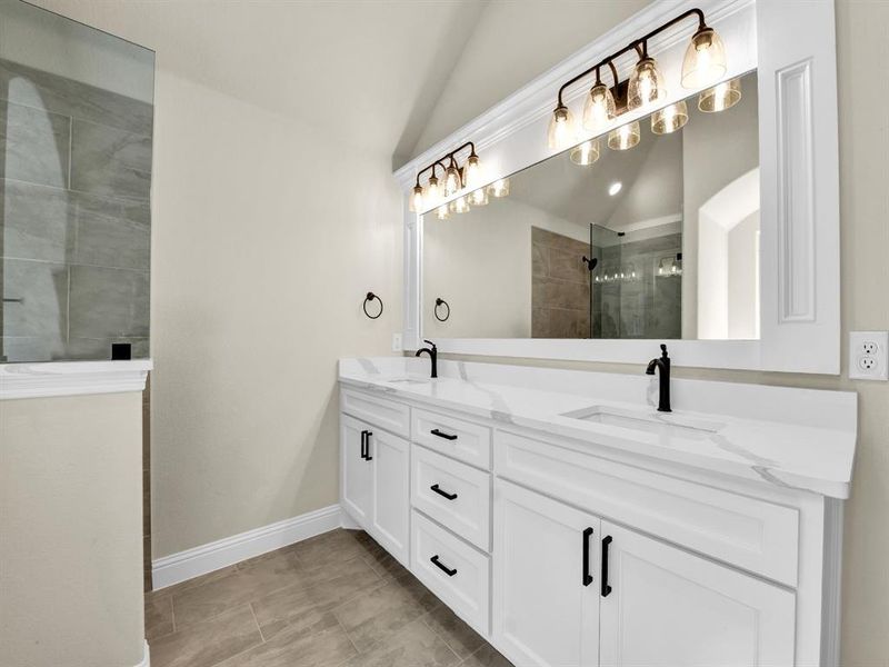 Bathroom with vanity, a tile shower, and vaulted ceiling