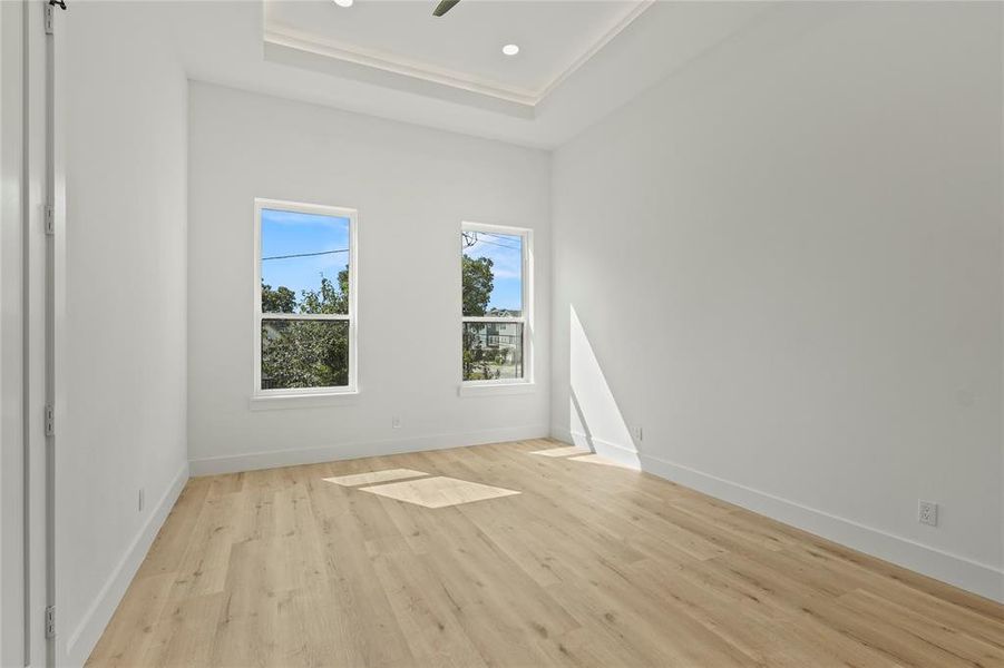 Spare room with recessed lighting, a tray ceiling, and light wood-style flooring