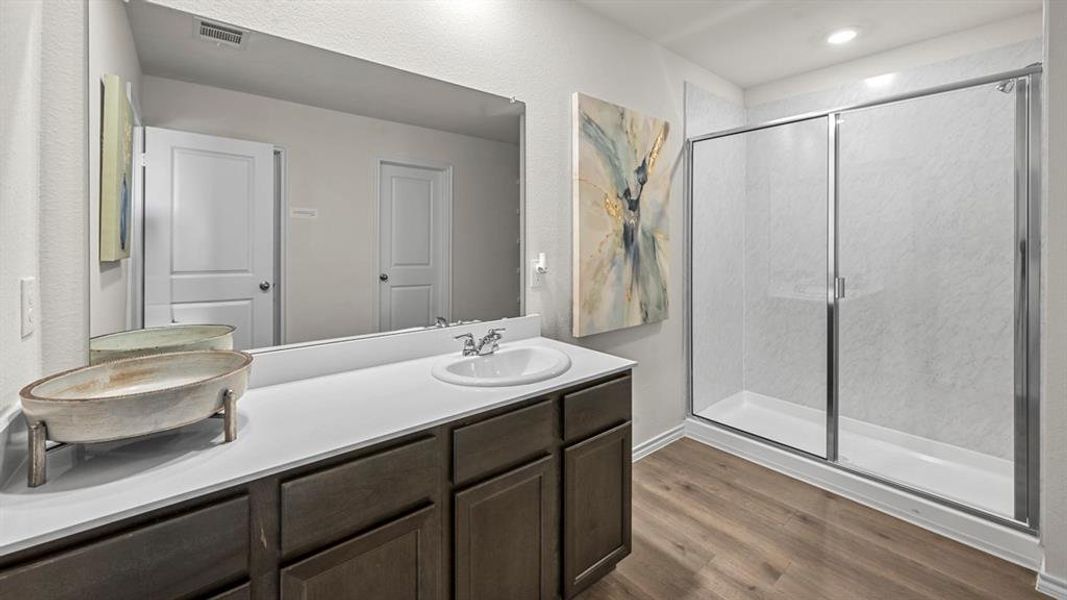 Full bath featuring double vanity, a shower stall, and dark wood-style floors