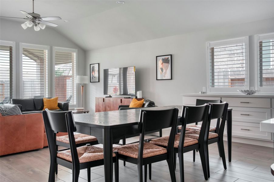 This bright, open-plan living and dining area features large windows with shutters, modern furnishings, and a ceiling fan. The space includes stylish seating, a dining table, and a TV, creating a comfortable and inviting environment. This bright, open-plan living and dining area features large windows with shutters, modern furnishings, and a ceiling fan. The space includes stylish seating, a dining table, and a TV, creating a comfortable and inviting environment.