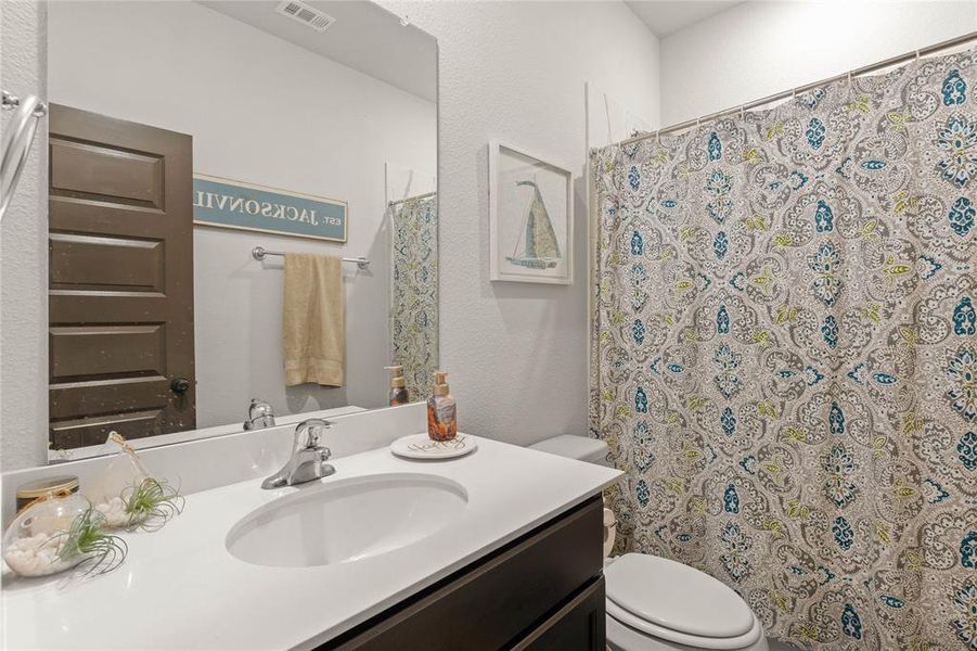 Downstairs full bathroom with vanity, a textured wall, and curtained shower