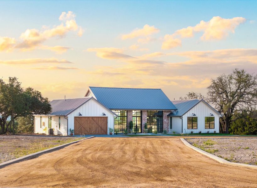 Modern farmhouse style home featuring board and batten siding, a metal roof, dirt driveway, and a standing seam roof