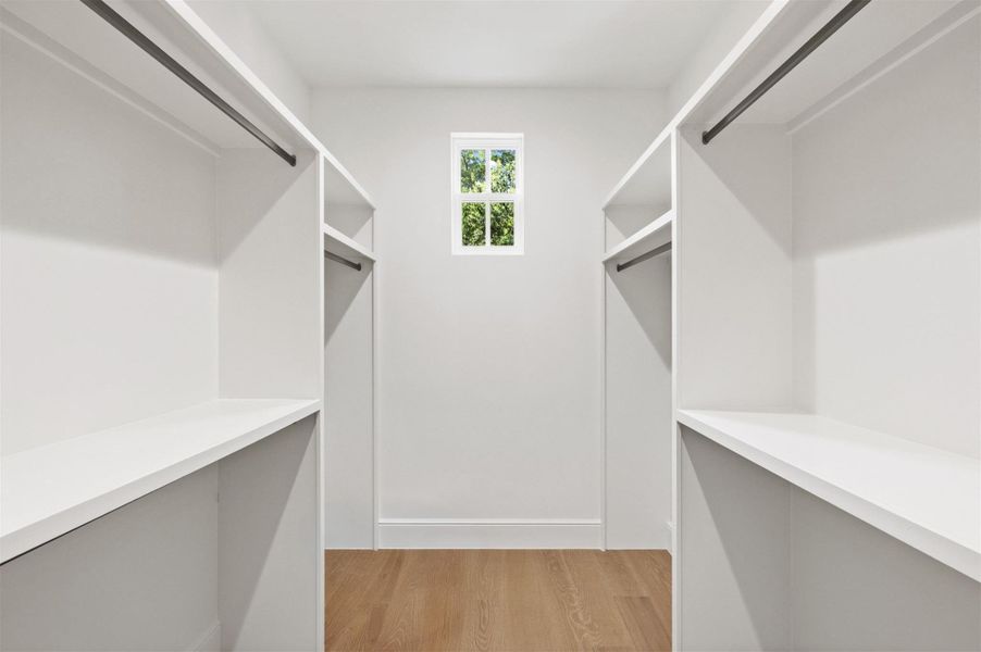 A well-lit walk-in closet features ample shelving and hanging space, illuminated by natural light.
