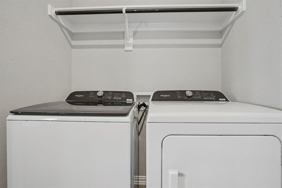 Laundry room with washing machine and dryer and a textured wall