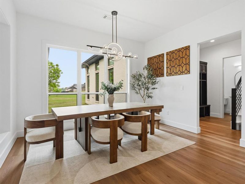Dining area featuring expansive windows, wood-finish flooring, a contemporary chandelier, and a built-in dark wood cabinetry