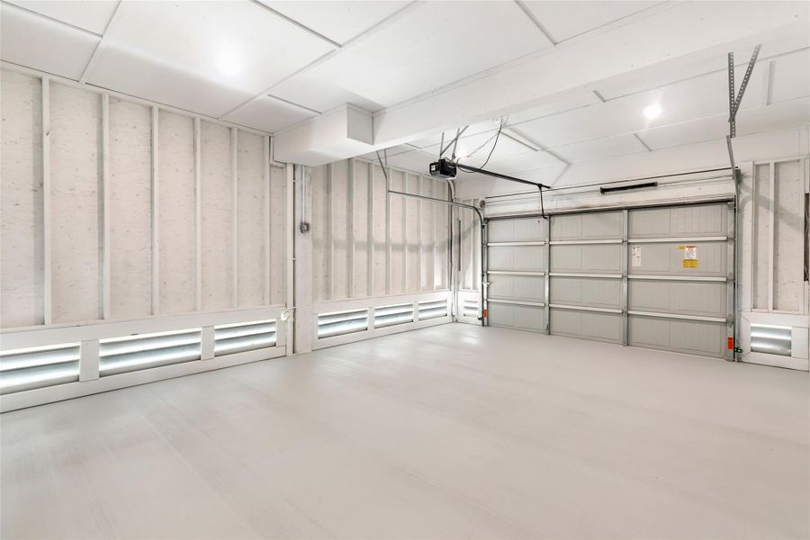 Oversized garage with ample space for a vehicle and workshop area.