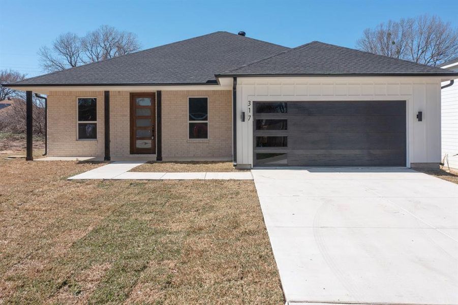 View of front of home featuring a garage and a front lawn