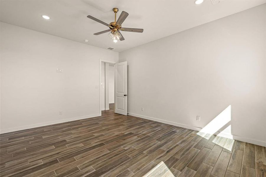 Empty room featuring dark wood-style floors, ceiling fan, baseboards, and recessed lighting