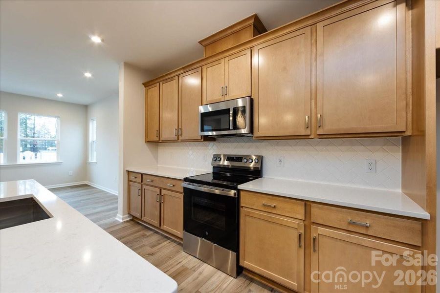 Chef's kitchen with Direct Vent, Stained Cabinetry, Quartz Cabinetry, and Herringbone Backsplash