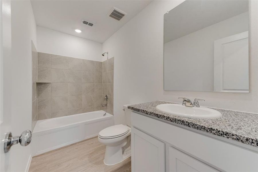 Full bathroom featuring toilet, hardwood / wood-style floors, vanity, and tiled shower / bath