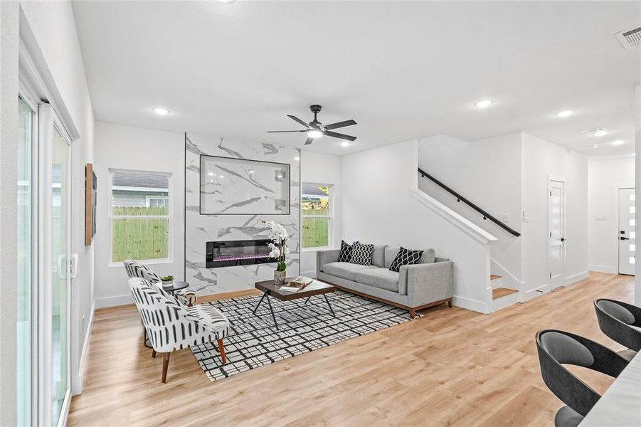 Living room featuring ceiling fan, a healthy amount of sunlight, light hardwood / wood-style flooring, and a high end fireplace