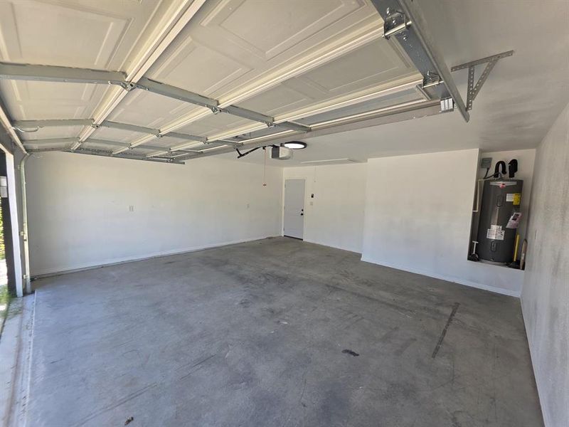 Garage featuring electric water heater and baseboards Garage featuring electric water heater and baseboards