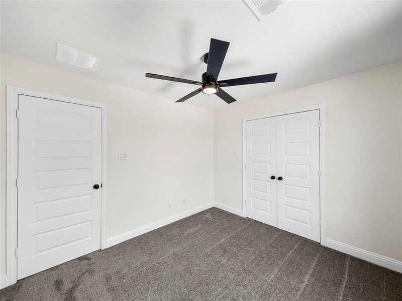 Unfurnished bedroom with dark colored carpet, ceiling fan, and a closet