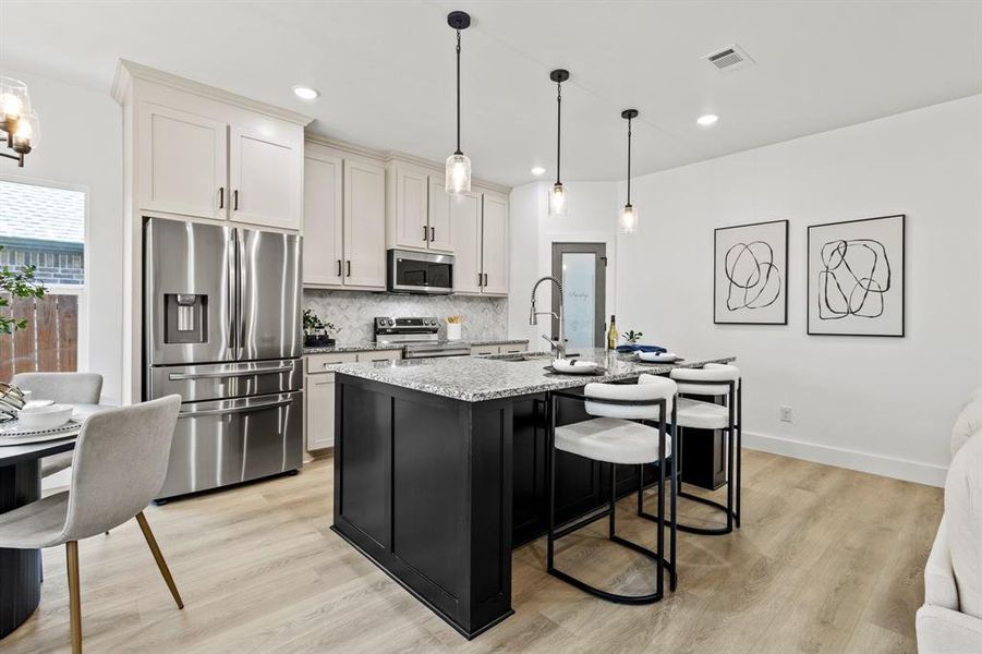 Kitchen featuring light stone countertops, visible vents, a sink, decorative backsplash, and appliances with stainless steel finishes