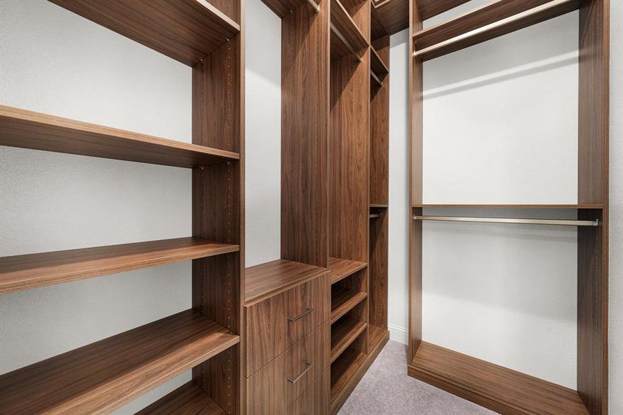One of two primary walk-in closets customized with shelves, drawers and hanging racks. One of two primary walk-in closets customized with shelves, drawers and hanging racks.