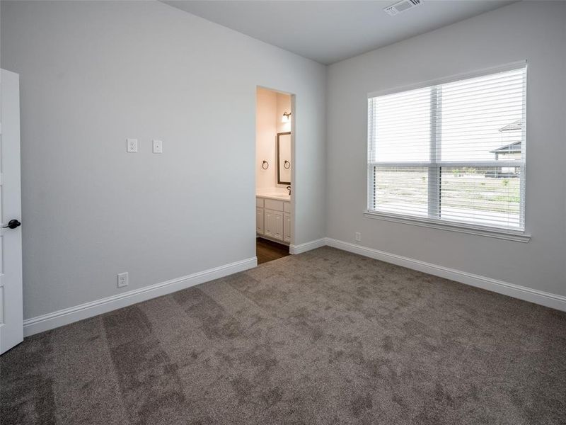 Unfurnished bedroom featuring dark colored carpet and connected bathroom