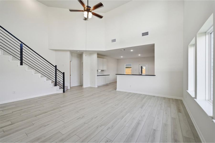 Spacious living area featuring light wood-finish flooring, soaring vaulted ceilings, and multiple windows