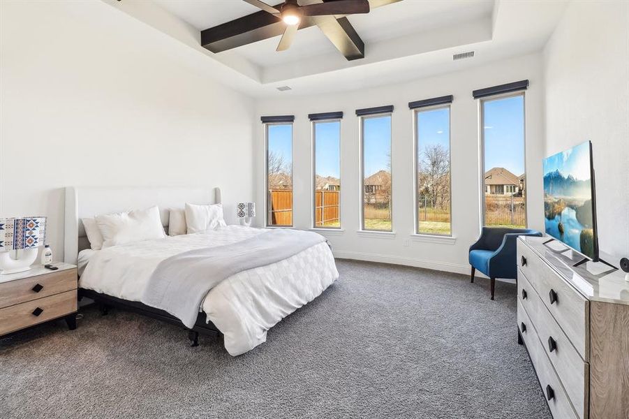 Bedroom featuring dark colored carpet, ceiling fan, coffered ceiling, and multiple windows Bedroom featuring dark colored carpet, ceiling fan, coffered ceiling, and multiple windows