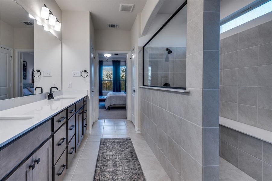 Full bathroom with ensuite bathroom, walk in shower, light tile patterned floors, and double vanity