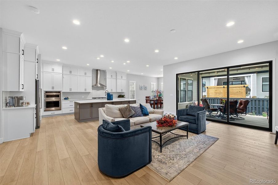 Kitchen and Dining Overview – Gourmet kitchen featuring crisp white cabinetry, a large center island with contrasting base, and stainless steel appliances, opening to a sunny dining area with multiple windows.