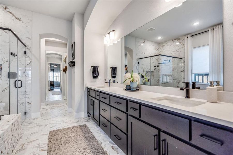 Full bath with a marble finish shower, double vanity, and light marble finish flooring