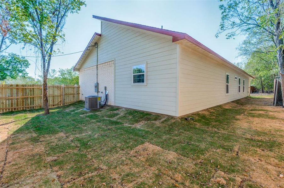 Back of property with central AC and a lawn