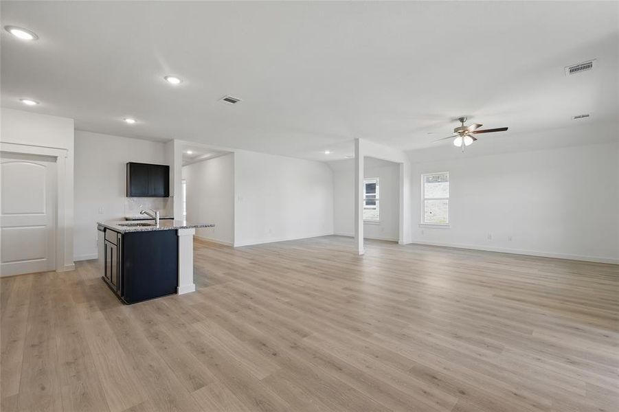 Unfurnished living room featuring light wood finished floors, visible vents, and a ceiling fan Unfurnished living room featuring light wood finished floors, visible vents, and a ceiling fan