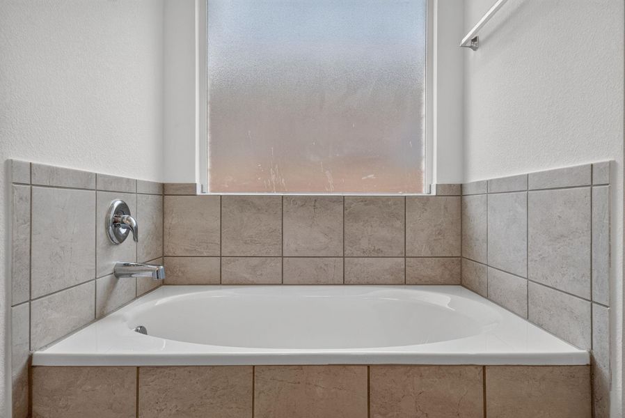 A well-maintained bathroom offers a clean bathtub, complemented by tiled walls and a privacy window. A well-maintained bathroom offers a clean bathtub, complemented by tiled walls and a privacy window.
