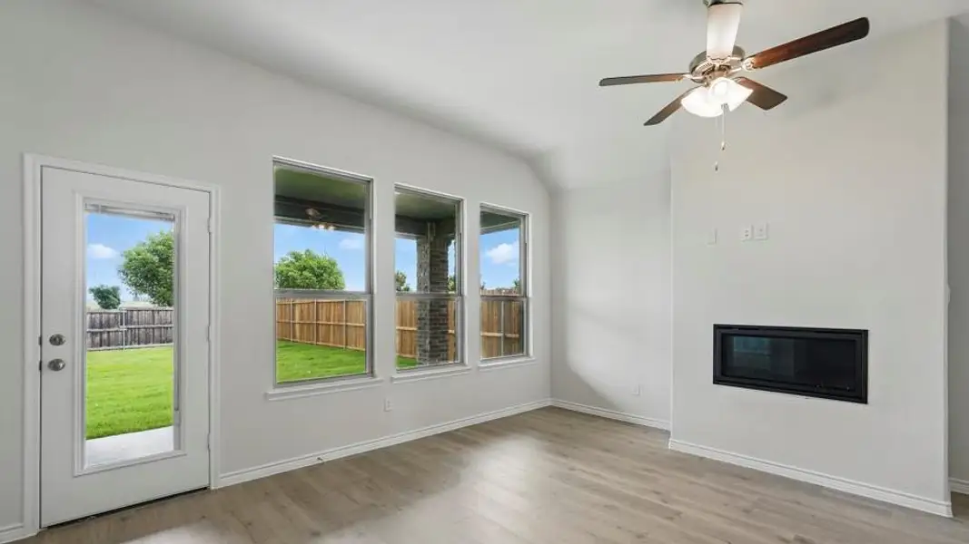 Unfurnished living room with light wood-style flooring, a glass covered fireplace, a ceiling fan, and lofted ceiling