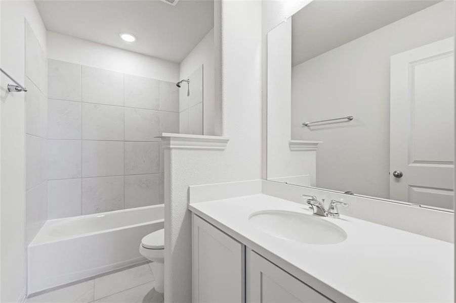 Contemporary bathroom featuring a tub/shower combination with large format tiled surround, a built-in vanity with an integrated sink, and a framed mirror