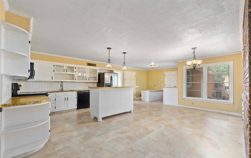Kitchen with crown molding, open shelves, white cabinetry, pendant lighting, and light countertops