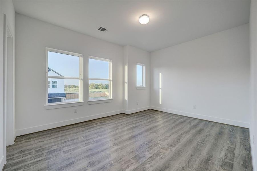 The secondary bedroom offers 10ft ceilings, large windows overlooking the front of the home, and durable LVP flooring throughout the room.