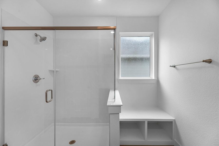 Spacious walk-in shower with sleek tile finishes, featuring a built-in side bench for added comfort and convenience.