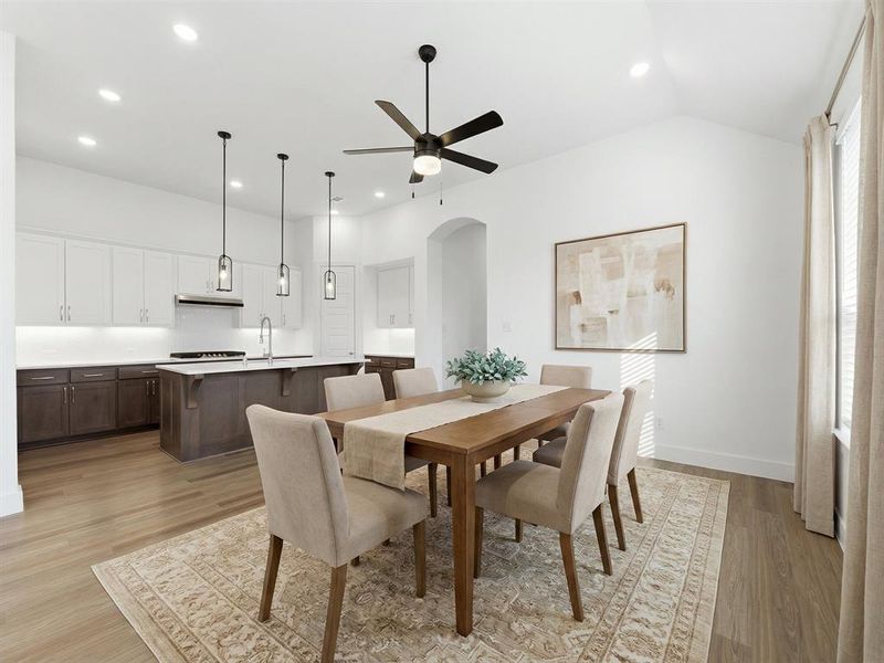 Virtually Staged Dining area featuring arched walkways, light wood finished floors, a ceiling fan, and recessed lighting