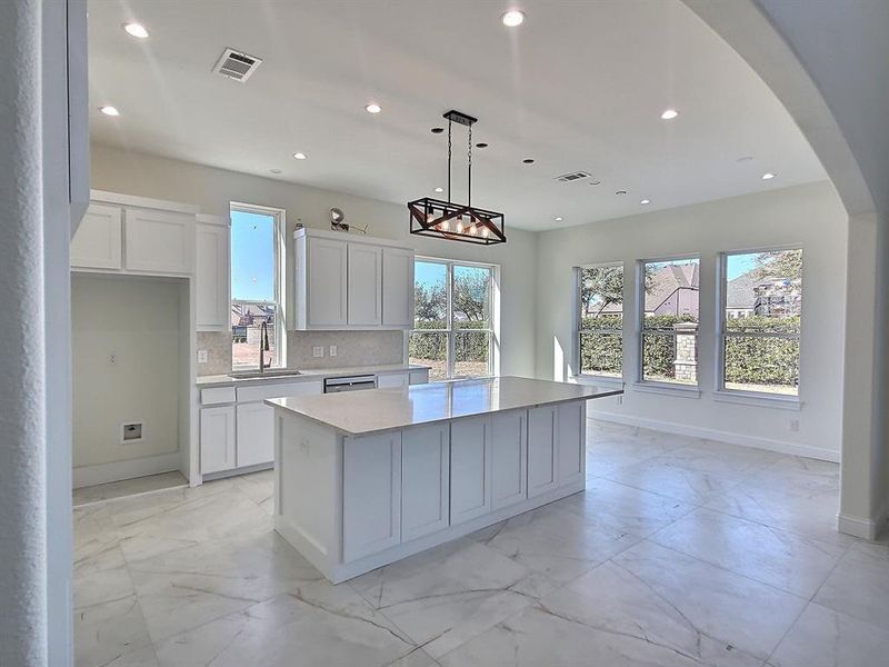 Kitchen with decorative backsplash, a center island, decorative light fixtures, white cabinets, and sink