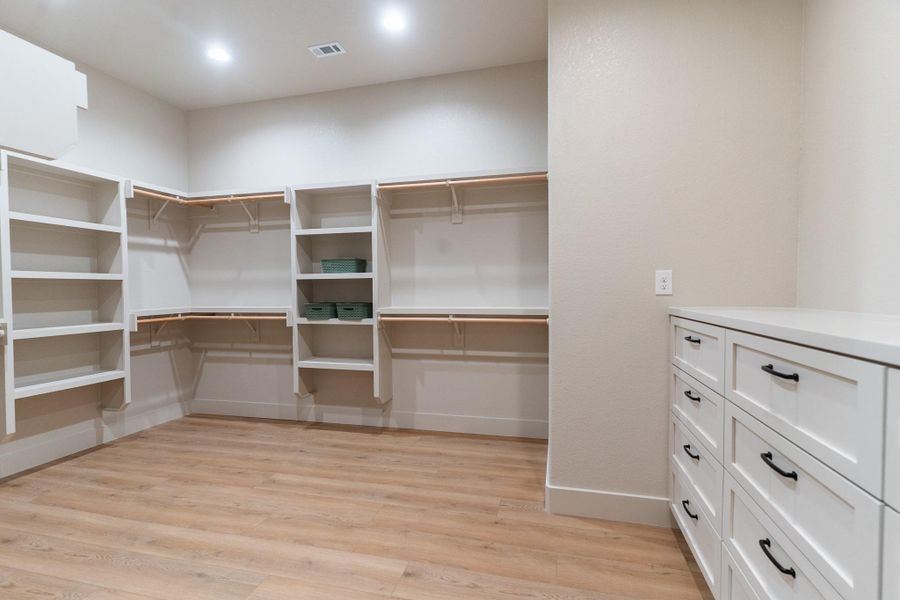 Walk in closet with light wood-style flooring Walk in closet with light wood-style flooring