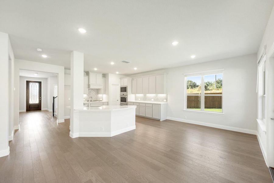 Open-concept living area and kitchen with white cabinets, center island, and hardwood floors