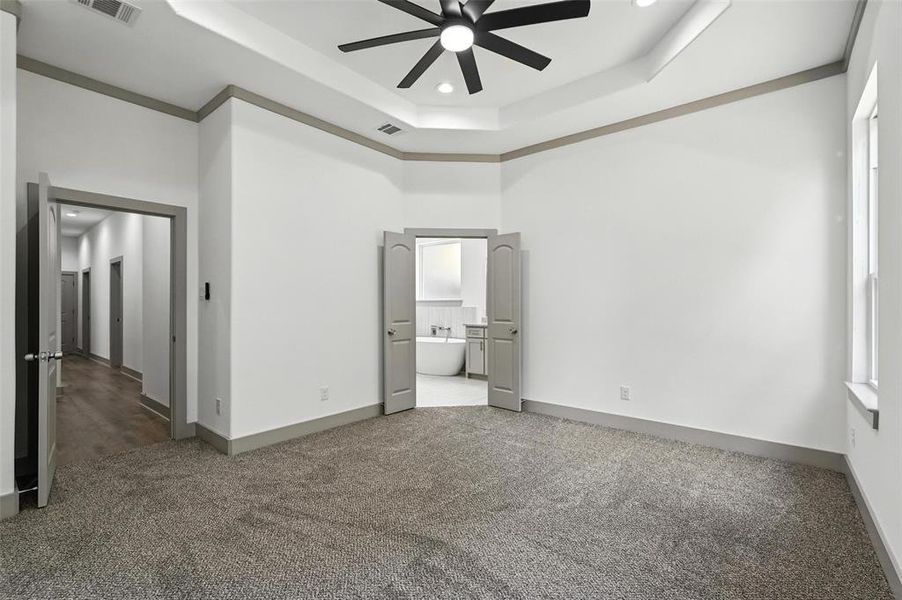 Unfurnished bedroom with connected bathroom, a raised ceiling, carpet, recessed lighting, and ceiling fan Unfurnished bedroom with connected bathroom, a raised ceiling, carpet, recessed lighting, and ceiling fan