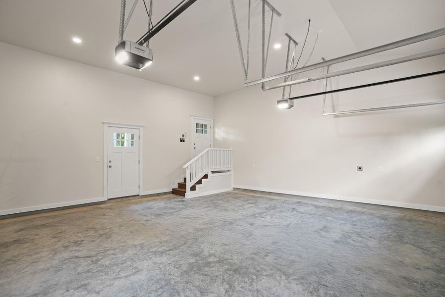 A spacious, well-lit garage with a practical staircase for interior access. A spacious, well-lit garage with a practical staircase for interior access.