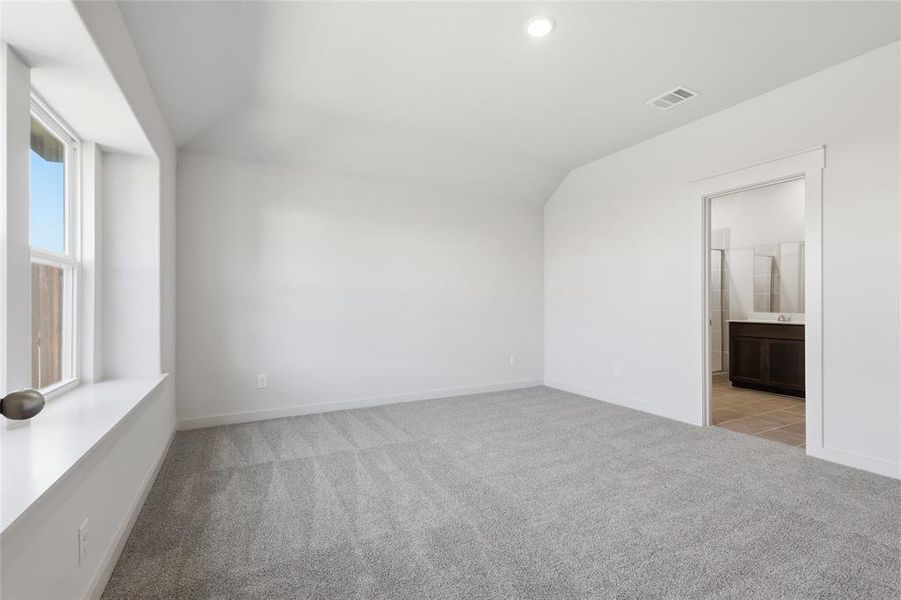 Unfurnished bedroom with light carpet, vaulted ceiling, ensuite bathroom, and recessed lighting