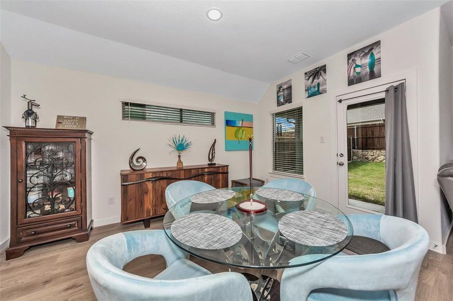 Dining room with vaulted ceiling, plenty of natural light, and hardwood / wood-style flooring