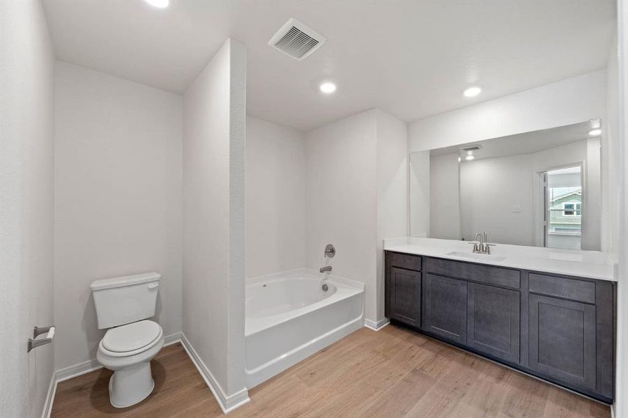 Bathroom featuring a washtub, vanity, wood-style floors, and toilet