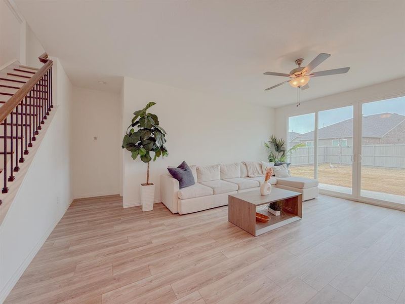 Living room featuring light wood finished floors, ceiling fan, stairway, and baseboards