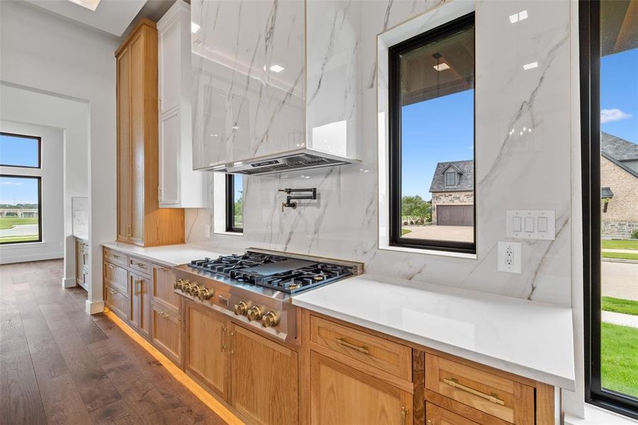 Kitchen with stainless steel gas cooktop, a healthy amount of sunlight, tasteful backsplash, and dark hardwood / wood-style flooring